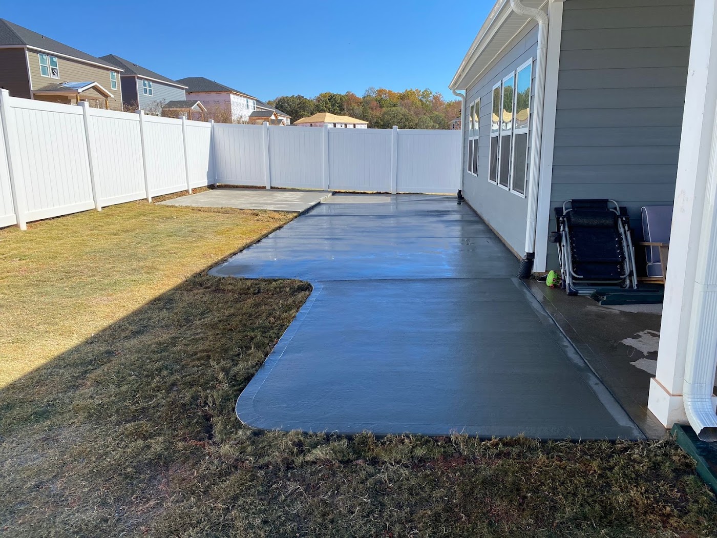 Large finished backyard concrete patio along the back of a home