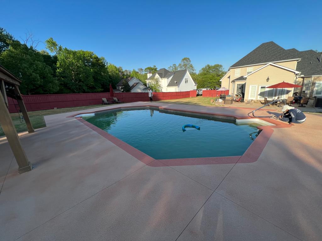 Concrete pool deck with a decorative border around an in-ground pool