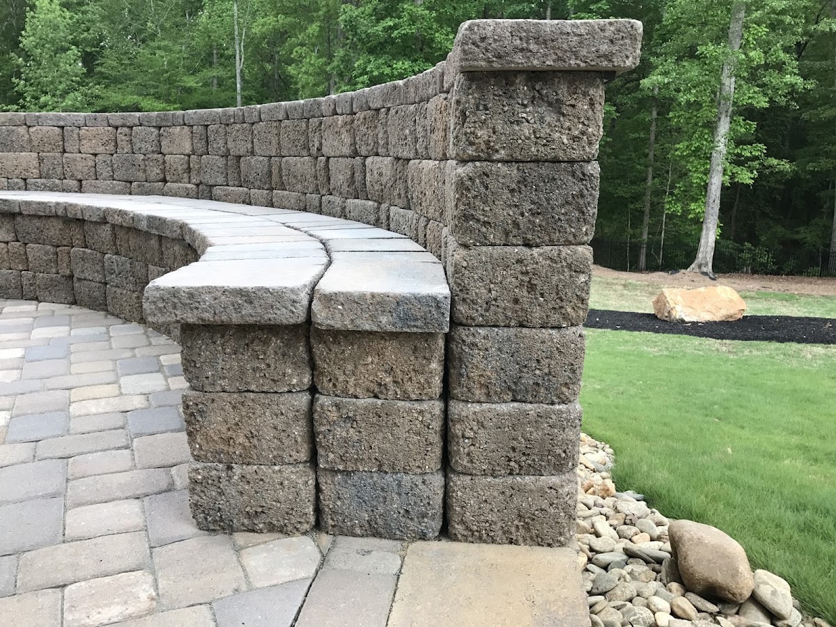 Stacked retaining wall with a built-in seating bench beside a paver patio