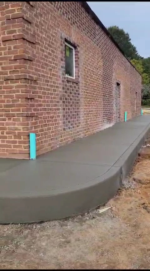 Curved concrete sidewalk poured along a brick building