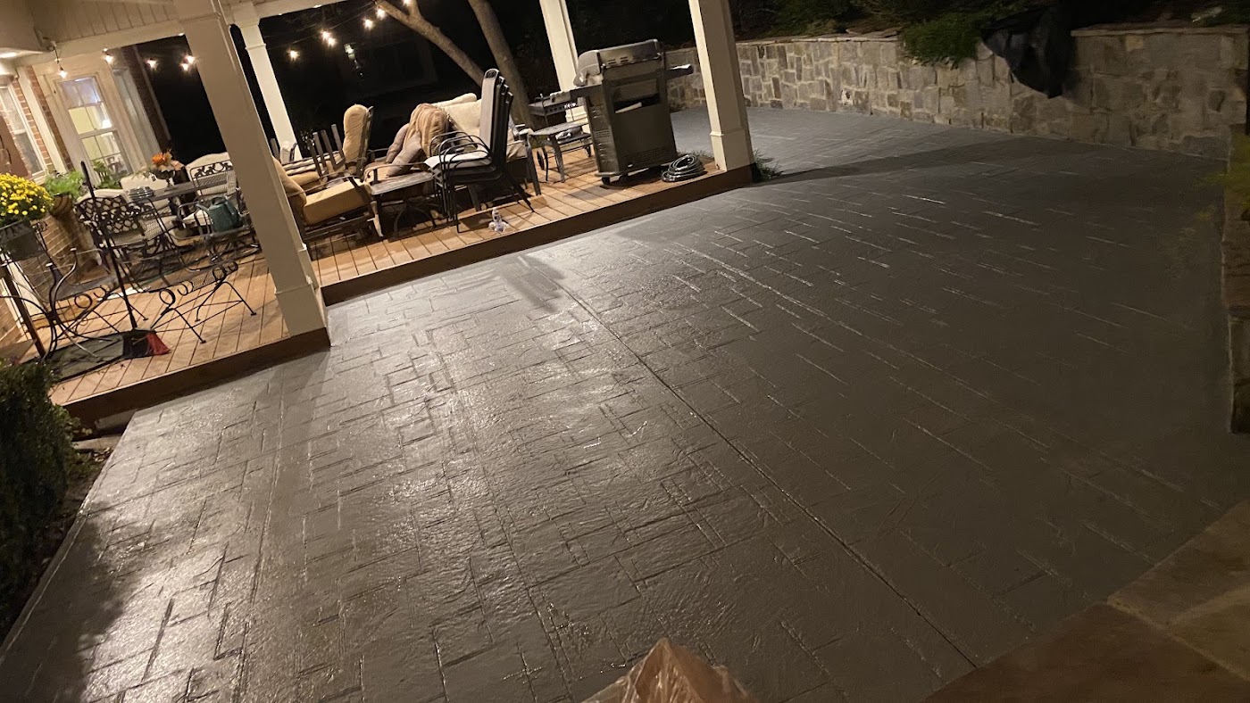 Stamped decorative concrete patio with a brick pattern under string lights