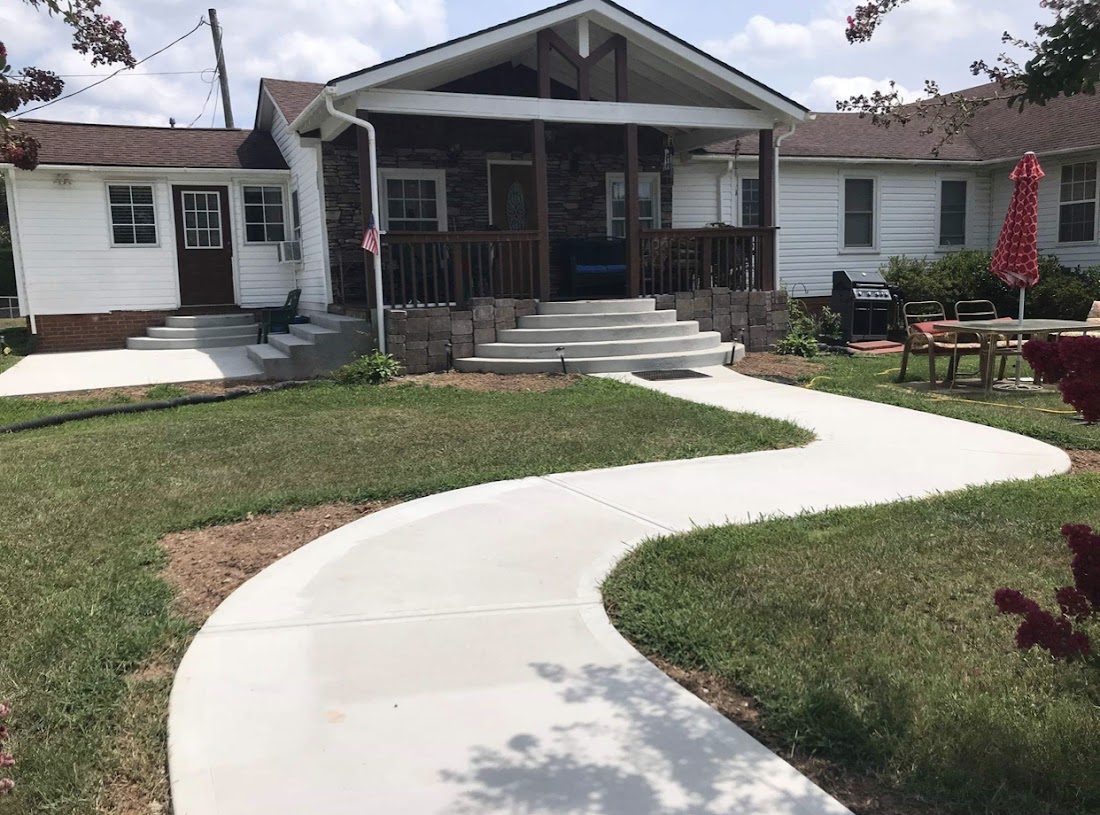 Curved concrete walkway leading to a covered front porch with steps